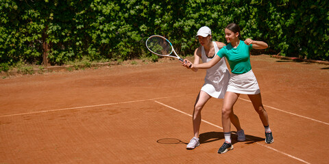 Naklejka premium Tennis coach teaches teenage girl racket control with copy space. Concept of youth academy, sports education, mentoring, tennis skills and summer camp ads.