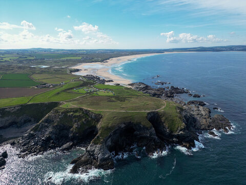 High‑Angle Aerial Drone View of Rugged Coastal Headland and Sandy Beach Under Clear Blue Sky, Pembrokeshire Coast, Wales, United Kingdom