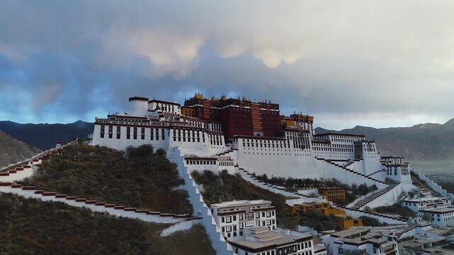 Aerial view of the Potala Palace at sunrise in Lhasa, Tibet, China, with the historic palace on the hill overlooking the city, surrounded by mountains and morning mist under golden light.