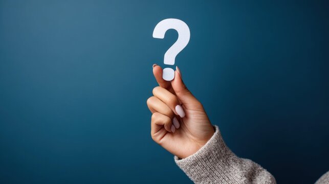 Woman's hand holding a white question mark symbol against a dark blue background