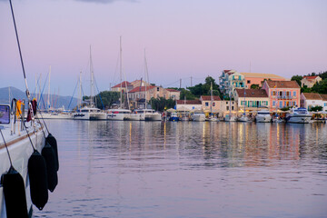 Obraz premium The Harbour of FGiskardo in Kefalonia with yachts and catamarans mooring. Fiskardo is a popular and busy harbour that often becomes a vibrant and hectic place to moor a boat.
