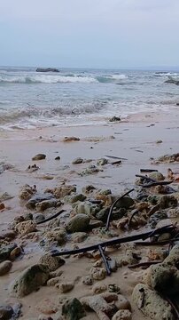 Sea waves and seafoam washing over rocky Radhanagar Beach shore.