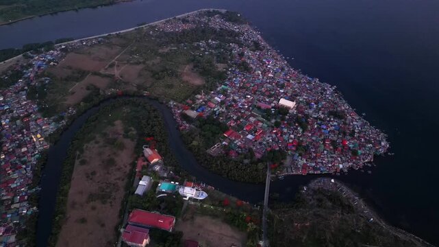 Wide angle aerial shot of riverside provincial homes along Calumpang River in Batangas City Philippines with scenic almost evening time landscapes.