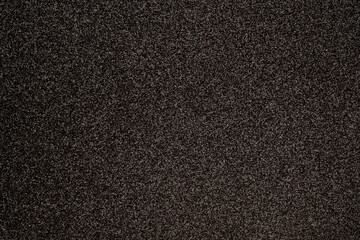 Fototapeta premium Dark textured surface with fine speckles, showing subtle reflective details suitable for backgrounds