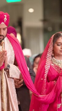 Vertical Shot of Sikh Bride and Groom with Folded Hands Praying During Traditional Anand Karaj Wedding Ceremony