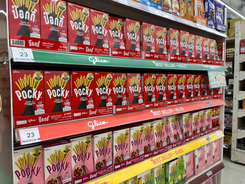 Pocky snack boxes displayed on supermarket shelves,featuring colorful Glico chocolate and strawberry biscuit stick packaging. Retail aisle with best seller signs,price tags, and confectionery products