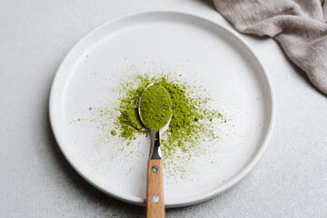 Naklejka premium Green matcha powder on a spoon over a white plate