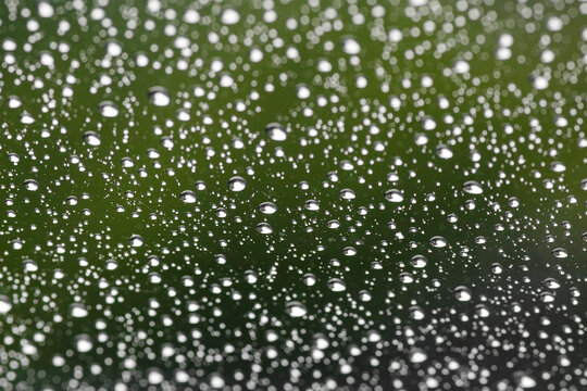 Water droplets on a window with green background