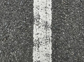 Fototapeta premium Close-up of a textured white line marking on dark asphalt pavement surface