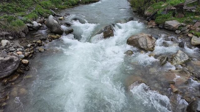 Fast flowing mountain stream cascading over rocks creating white water rapids in a peaceful forest setting, Enguri river, Svaneti, Georgia