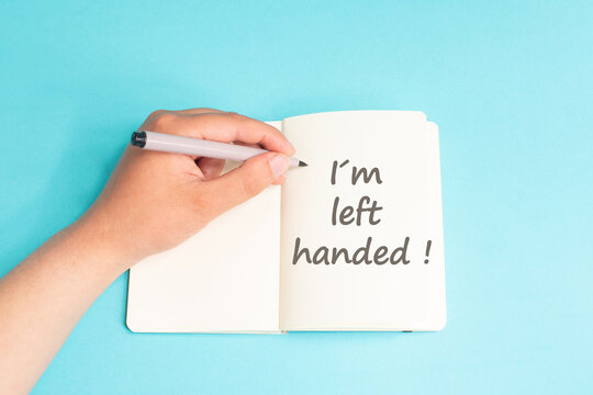 I am left handed is standing on notebook, writing with left hand, pen and table, lefty concept, handwriting a message