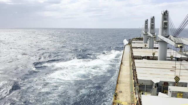 cargo ship proceeding in heavy weather in ocean. water spray on deck, but vessel continue his voyage