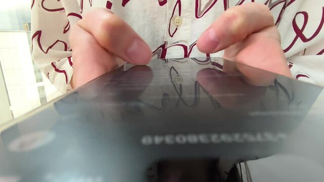 Close up hands tap on a smartphone screen. Fingers move across the glass while the phone stays in frame. Mobile app use and online browsing concept..