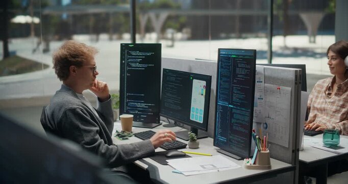 Two Software Engineers Debug Software and Test a Mobile App Prototype on Multi-monitor Workstations, Comparing Code, Interface Screens, Development Office.  Working Using Computer