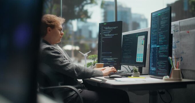 Young App Engineer Starts a Coding Day With Hand Warm-up, Then Writes Source Code Across Vertical Monitors While Checking a Mobile Ui Charts,  Video Game Development Office.  Working Using Computer