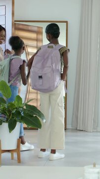Vertical video: Door opening at home, mom greeting, teen adjusting lavender backpack, leaving