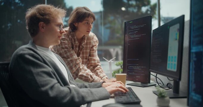 Female Engineer Consults a Male Designer Through Mobile App Interface Design, Code Fixes, Mapping AI Ecommerce Logic, API Security and Product Architecture on Stacked Monitors in Software Dev Office