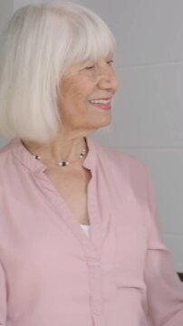 Vertical video: Arriving carer hugging senior at doorway during check-in, comforting in scrubs