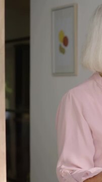 Vertical video: Coming caregiver hugging senior at door, greeting, scrubs, necklace, copy space