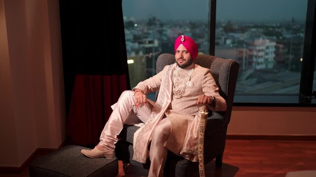Wide Shot of Royal Sikh Groom Sitting on Sofa with Kirpal and Smiling in the Camera