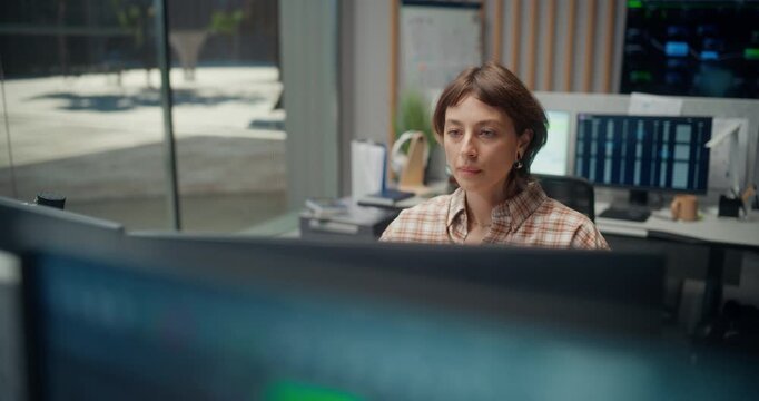 Portrait of Young Female Software Engineer Using Computer, Interact with Dashboards Across Monitors in Modern Office, Mobile Ecommerce Video Game, AI Use, Health App and Cybersecurity