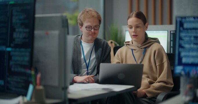 Two Caucasian App Developers, Discuss Coding Strategy on a Laptop in Tech Office, Reviewing Software Features, Cybersecurity Layers and Ecommerce Ux Design.