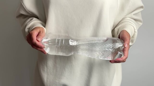 Female showing a half empty plastic bottle for recycling and eco awareness