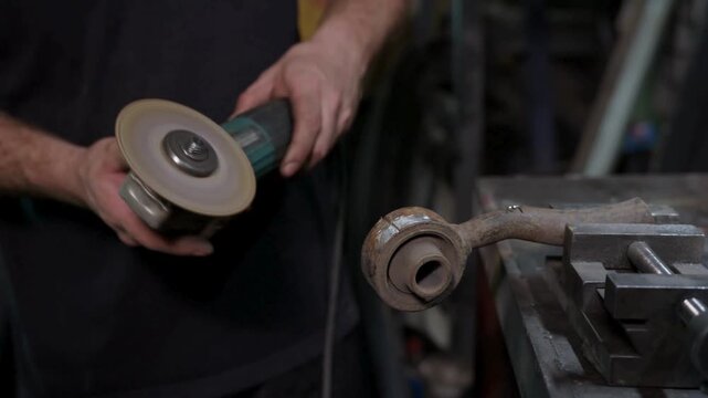 Technician aligns abrasive wheel against metal tube for careful workshop fabrication
