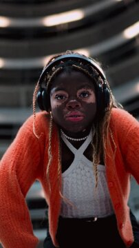Portrait of black female with vitiligo skin looking thoughtfully at camera while standing in spiral architecture of underground. African American young woman attentively look at you 
