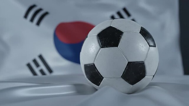 A cinematic sequence featuring a soccer ball on white silk, set against the South Korean flag. It captures national sports pride and athletic excellence through elegant lighting and framing.