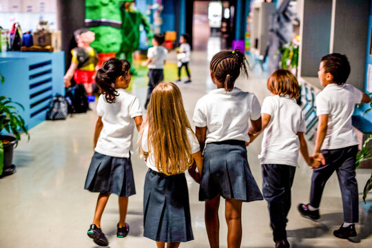 Children walking school hallway together.