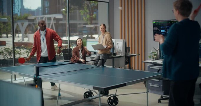 Energetic Tech Professionals Play Ping Pong Office. Cheerful Software Developers and Engineers have Game of Table Tennis Between Coding Sprints, Surrounded by Monitors Displaying Code and Data.