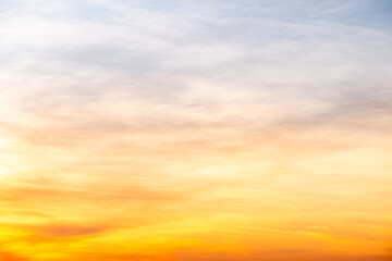 Naklejka premium Sky sunset,Beautiful sunrise sky with vibrant gradient orange and gold colors and soft blue, Clear atmosphere with wispy clouds. Peaceful, perfect for background and copy space, High resolution images