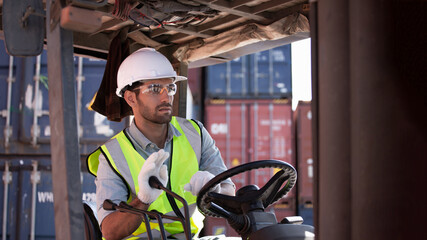 Focused worker operates forklift within busy shipping container yard while wearing safety glasses, high-visibility vest, and protective gloves for safe logistics operations emphasizing cautious © AU USAnakul