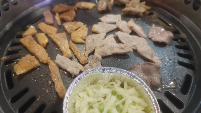 Dolly in of Korean barbecue tabletop grill with marinated pork beef slices traditional rolled egg gyeran mari and melted cheese cup sizzling 