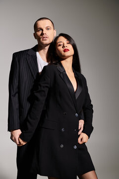 A stylish young couple in trendy attire posing with love in a chic studio.