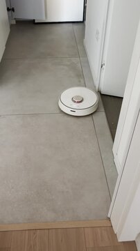 Round cleaner robot passing by hallway in house cleaning floor and sweeping parquet in apartment. Funny video ugc pov style vertical phone reel. Social media. Automatically cleaning device technology