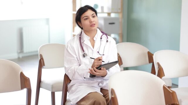 Female doctor at meeting listens to teacher and and using tablet to write down notes. Off-line training, first Aid course.