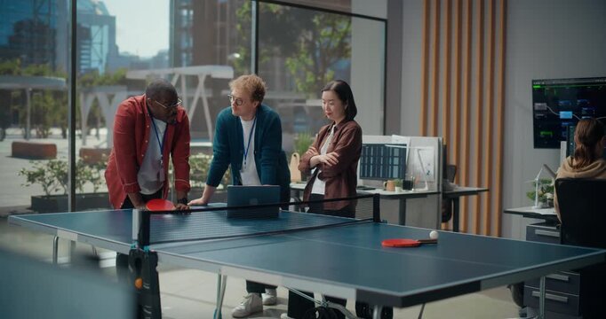 Three Young Software Developers Meeting Gather at Table For Office Meeting. Black Man, White Man,  Asian Woman Collaborate on App Coding, Algorithms and Cybersecurity Engineering Solutions.