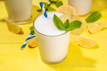 Fototapeta premium Whipped lemonade or mojito cocktail, lemonade milkshake. Italian summer alcoholic cocktail Sgroppino. Viral Brazilian lemonade. Two servings in glasses and jar, with fresh lemons and mint