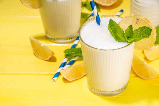 Whipped lemonade or mojito cocktail, lemonade milkshake. Italian summer alcoholic cocktail Sgroppino. Viral Brazilian lemonade. Two servings in glasses and jar, with fresh lemons and mint