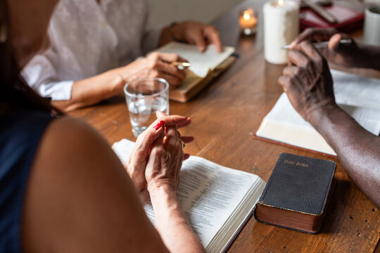 Diverse group of adults reading and praying at a wooden table