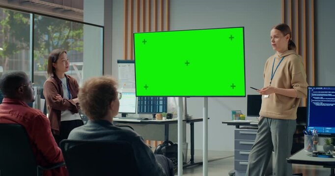 Office Meeting Presentation: Young Woman Leader Presents Beside Green Screen Chroma Key Display as Diverse Software Team Discusses App, Engineering Ecommerce App, Video Game Development Meeting
