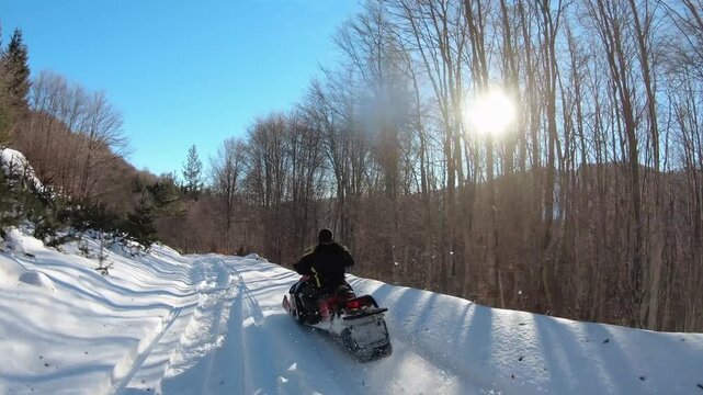 Fast snowmobile ride through scenic forested snowy path on a sunny winter day