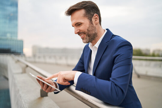 Smiling businessman using digital tablet outdoors in a city
