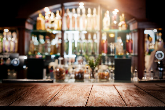Empty rustic wooden table top or bar counter with copy space for product placement, display or mockup. Abstract blurred background of a cozy restaurant, cafe, pub or night club interior with glowing