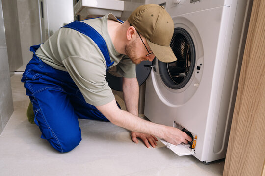 Male professional repairman inspecting modern washing machine