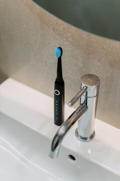 Modern electric toothbrush on white sink in a contemporary bathroom