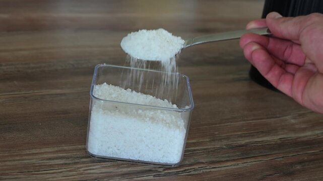 scoop of corse kosher salt falling, out of the scoop in to the pot in slow motion, chef, kitchen