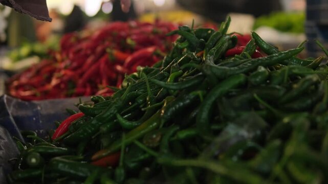 Local market culture authentic street market life with fresh red and green chili peppers, hand selecting produce at busy bazaar stall, real lifestyle concept